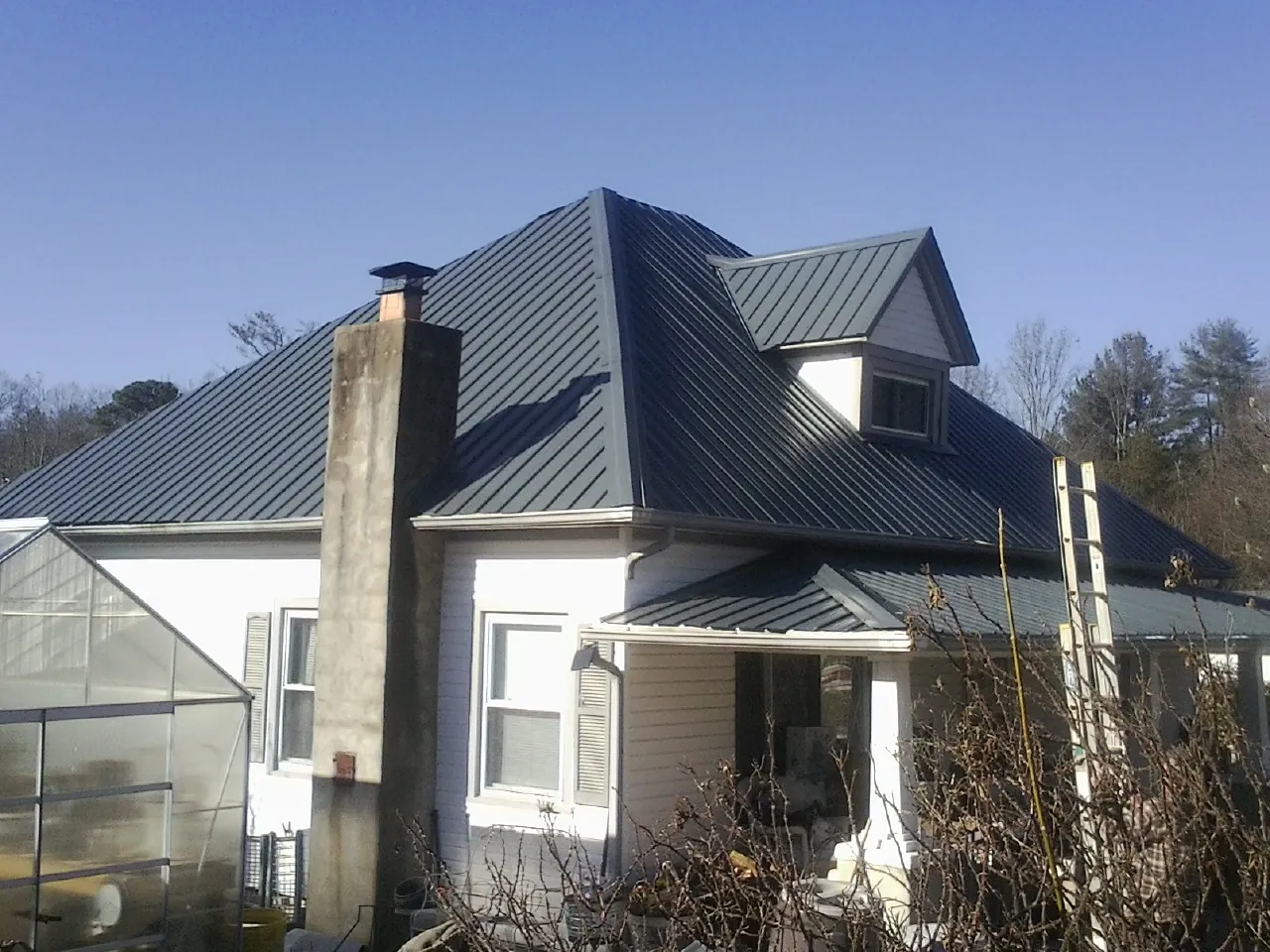 Dark blue standing seam metal roof on a white farmhouse with dormer — Slate & Tile Roof Repair by Roofing Brothers in West Milford