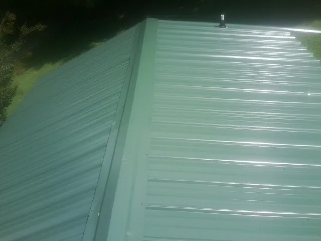 New green metal panels meeting at the ridge of a roof — Flat Roof Repair work by our crew in West Milford