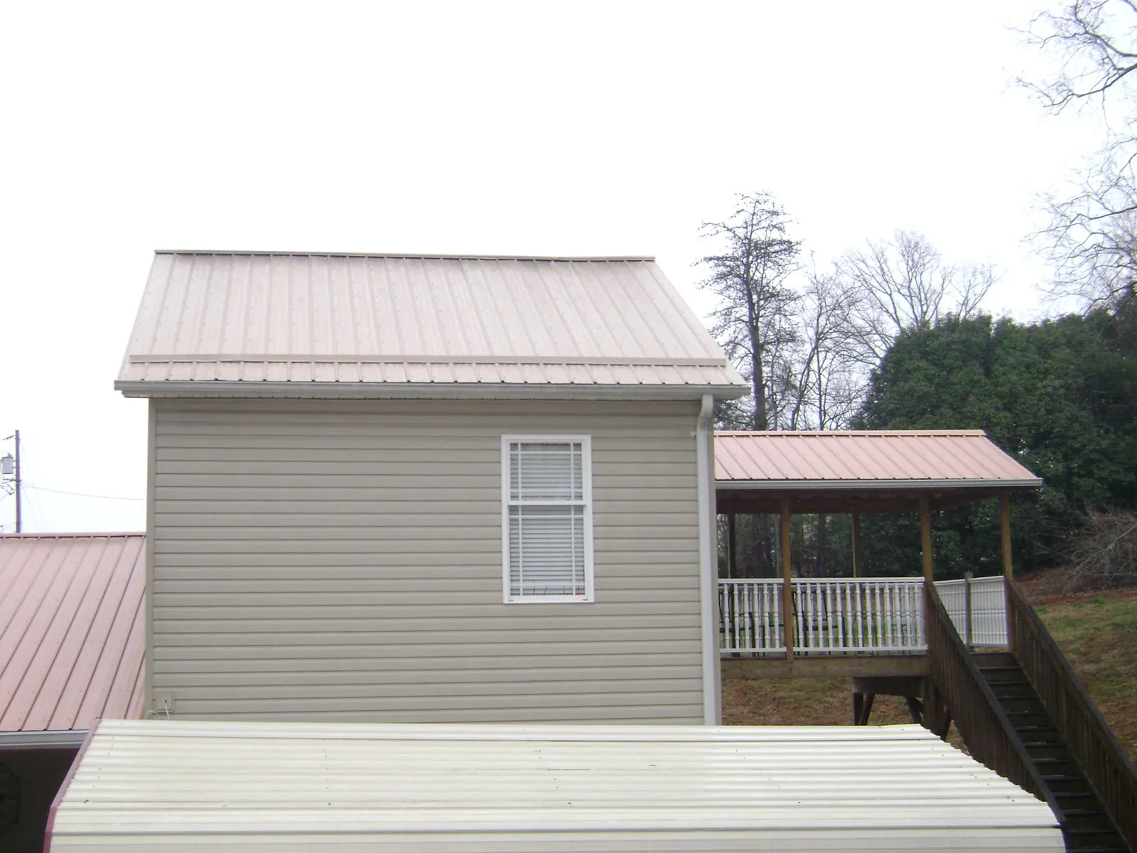 Tan metal roofs on a two story addition and attached porch, from a Roof Replacement job in West Milford