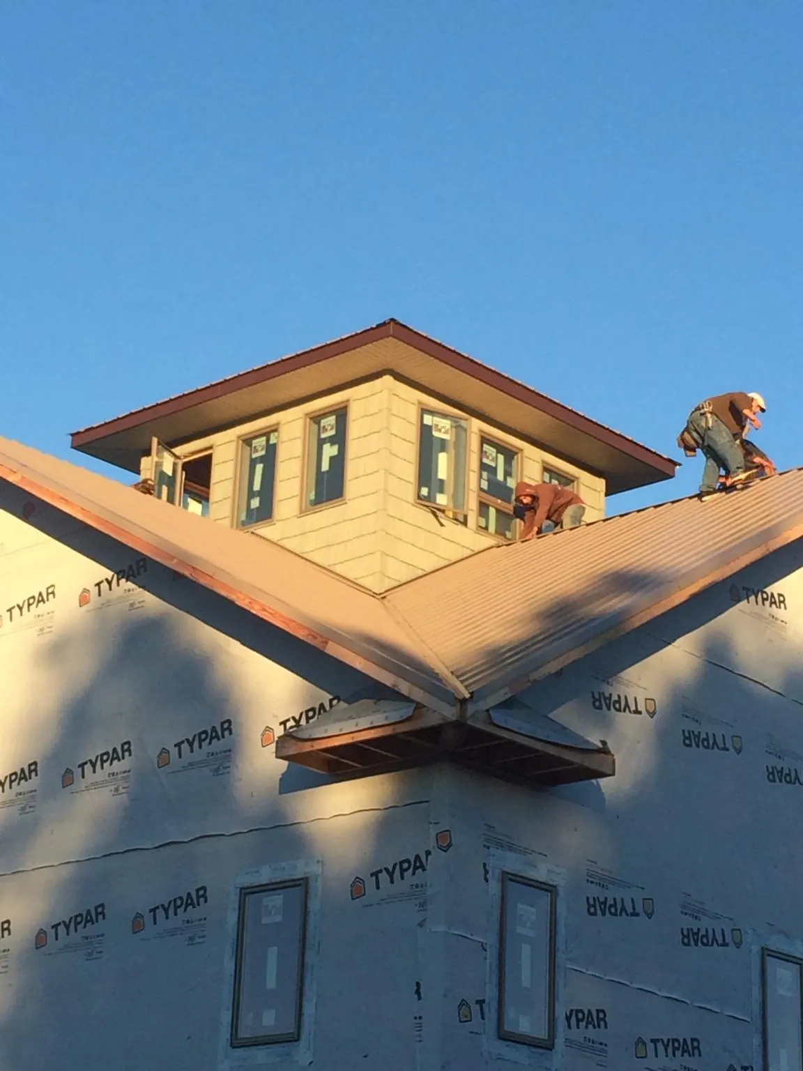 Roofers working around a rooftop cupola on a new metal roof at sunset — Roof Waterproofing in West Milford by Roofing Brothers